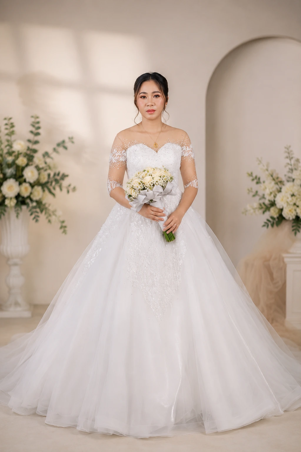 Bride wearing a white ball gown wedding dress with lace sleeves and sparkling details from Myra’s Bridal Boutique.